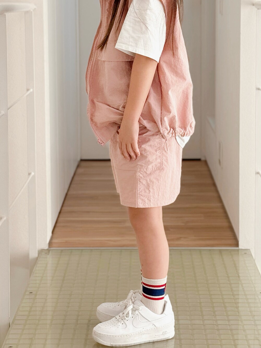 ホワイト系のスニーカー、ホワイト系のTシャツ/カットソー、ピンク系のベストを着用したキッズの春コーディネートの3枚目の写真