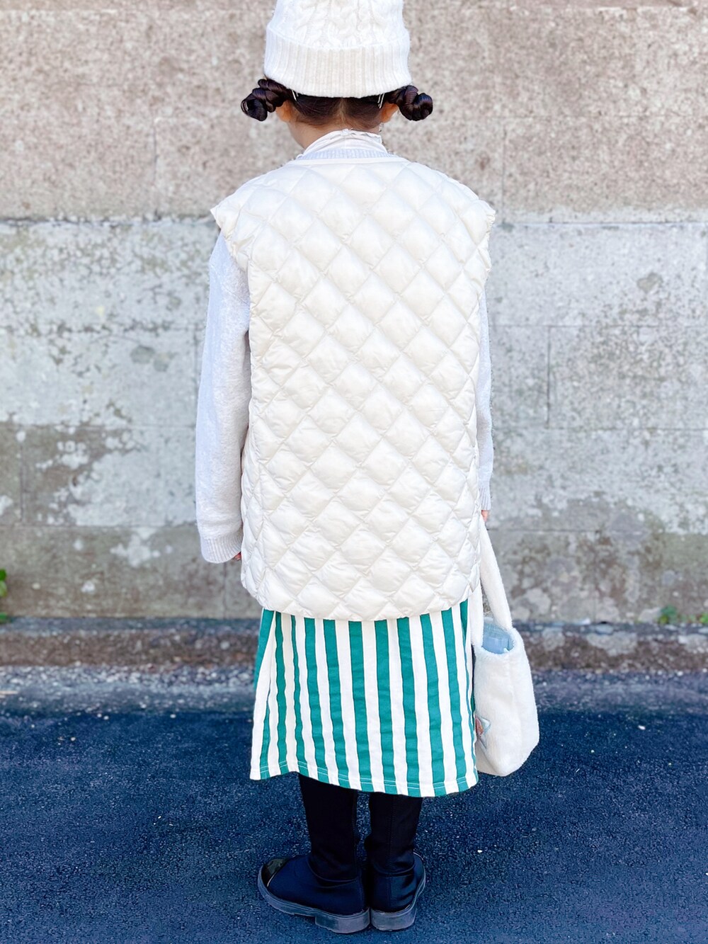 ホワイト系のベスト、グレー系のニット/セーター、ホワイト系のTシャツ/カットソーを着用したキッズの冬コーディネートの3枚目の写真