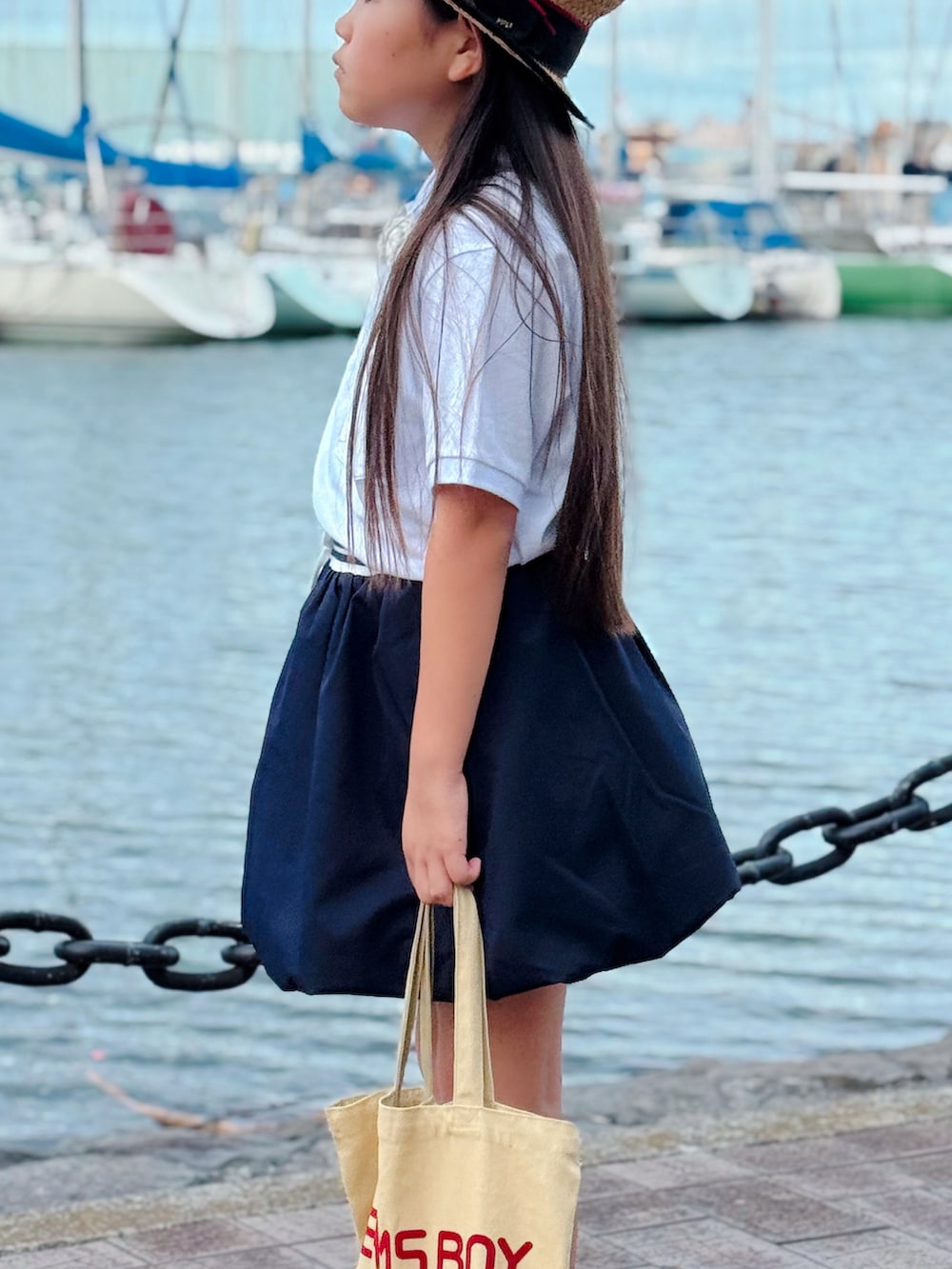 ホワイト系のスニーカー、ホワイト系のポロシャツ、ブルー系のスカートを着用したキッズの夏コーディネートの2枚目の写真