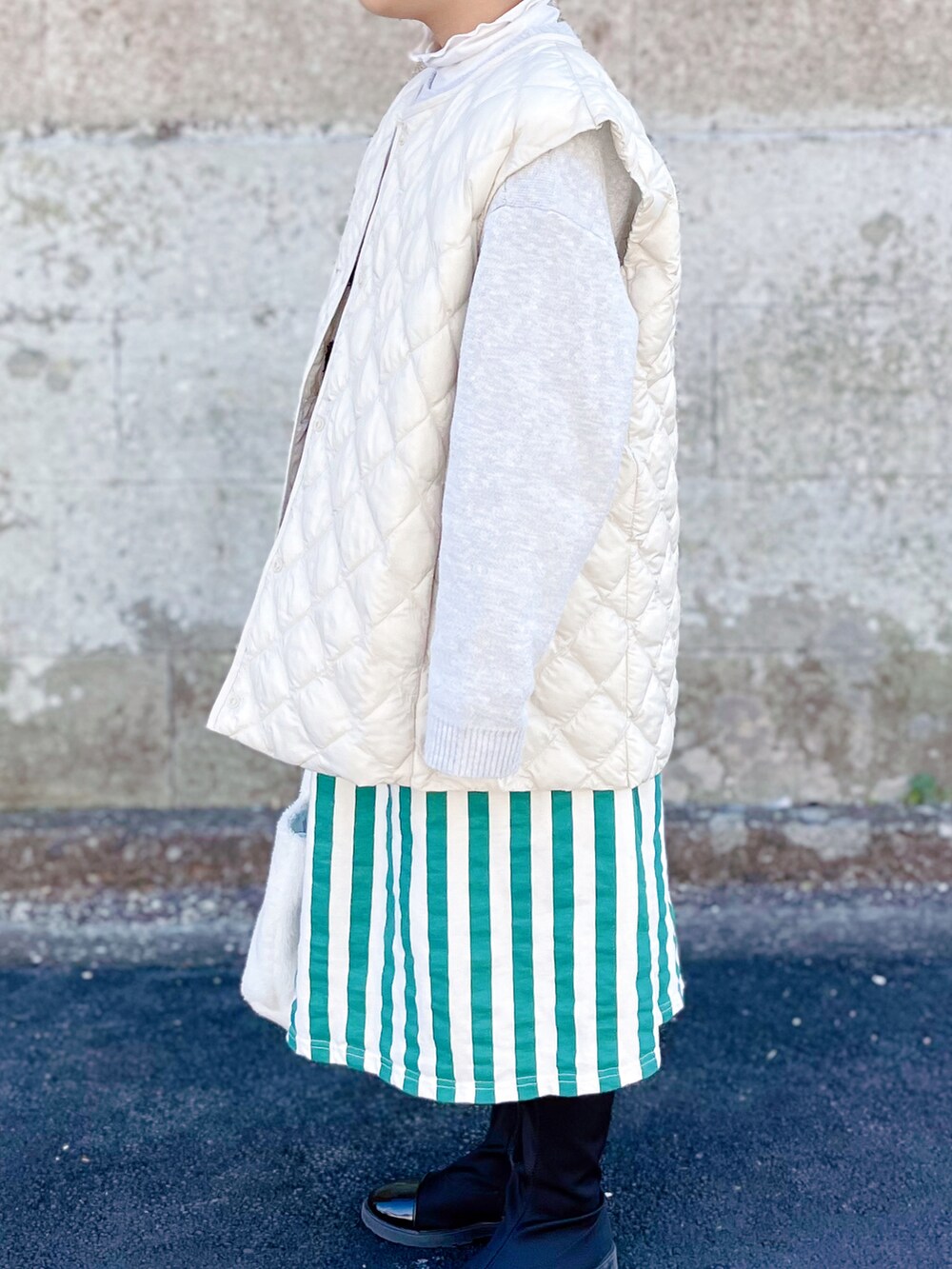 ホワイト系のベスト、グレー系のニット/セーター、ホワイト系のTシャツ/カットソーを着用したキッズの冬コーディネートの2枚目の写真