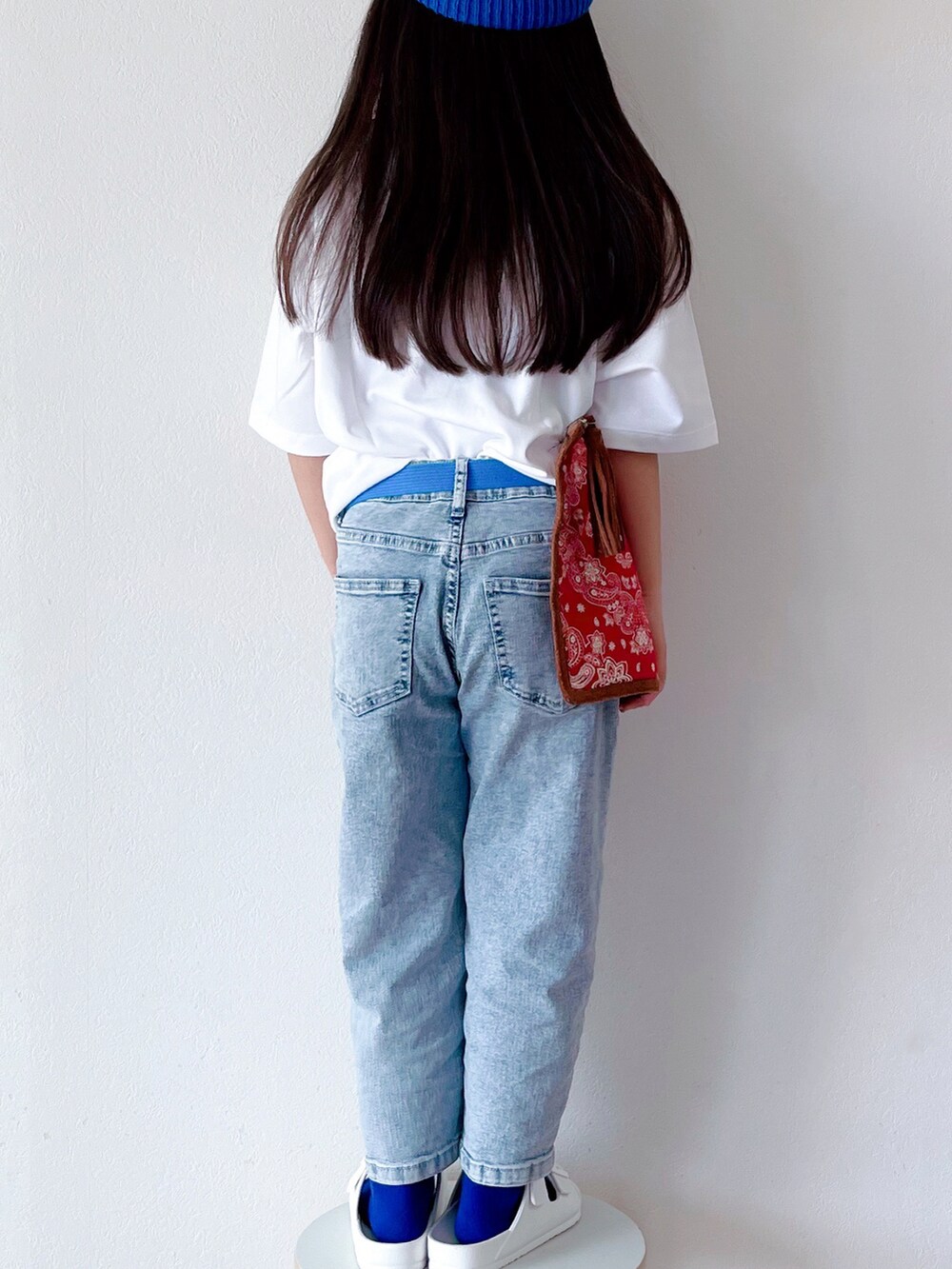 ホワイト系のTシャツ/カットソー、ブルー系のデニムパンツ、レッド系のクラッチバッグを着用したキッズの春コーディネートの3枚目の写真