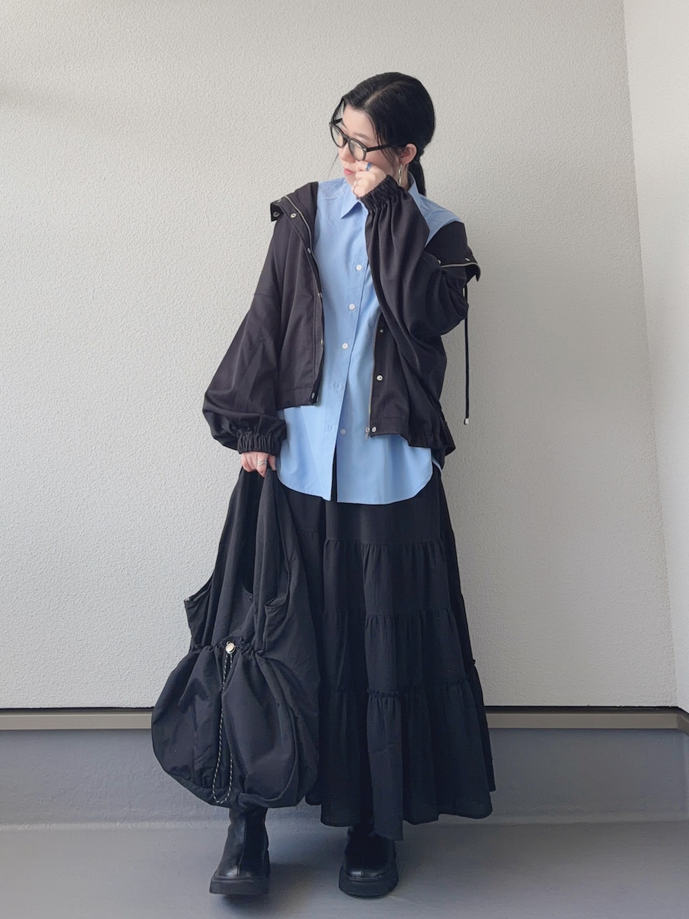 ブラック系のマウンテンパーカー、ブラック系のブーツ、ブラック系のトートバッグを着用したレディースの春コーディネートの5枚目の写真