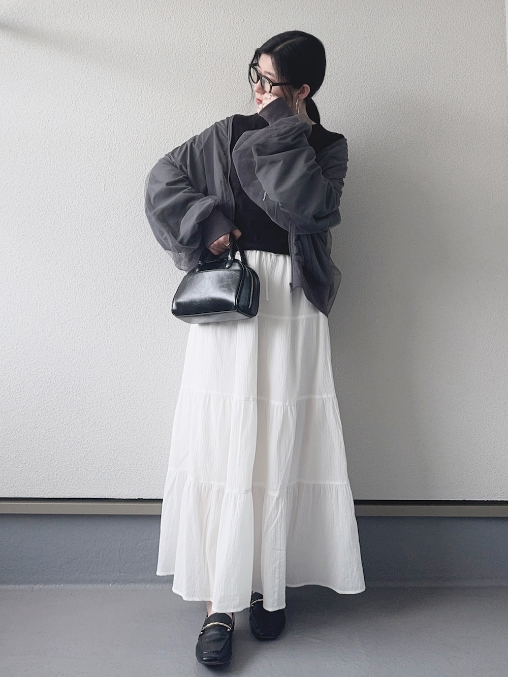 グレー系のブルゾン、ブラック系のTシャツ/カットソー、ホワイト系のスカートを着用したレディースの春コーディネートの4枚目の写真