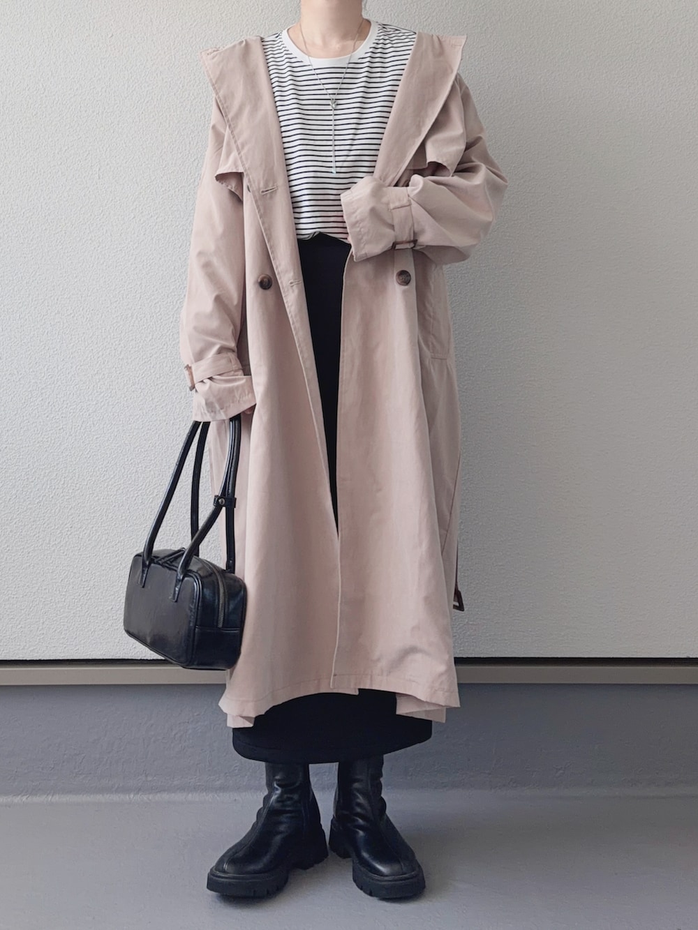 ベージュ系のトレンチコート、ブラック系のブーツ、ホワイト系のTシャツ/カットソーを着用したレディースの春コーディネートの2枚目の写真