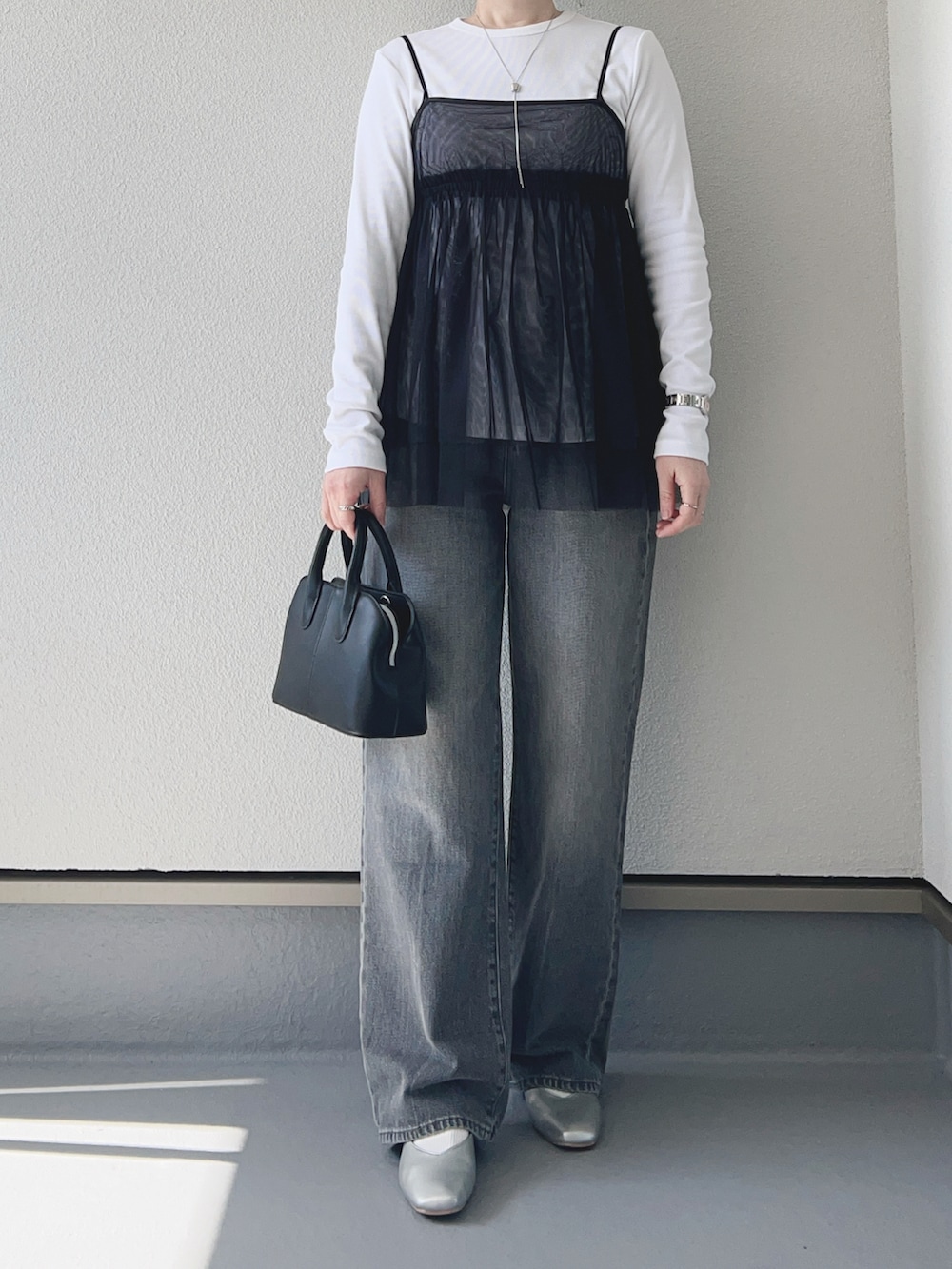 ブラック系のキャミソール、ホワイト系のTシャツ/カットソー、グレー系のデニムパンツを着用したレディースの冬コーディネートの2枚目の写真