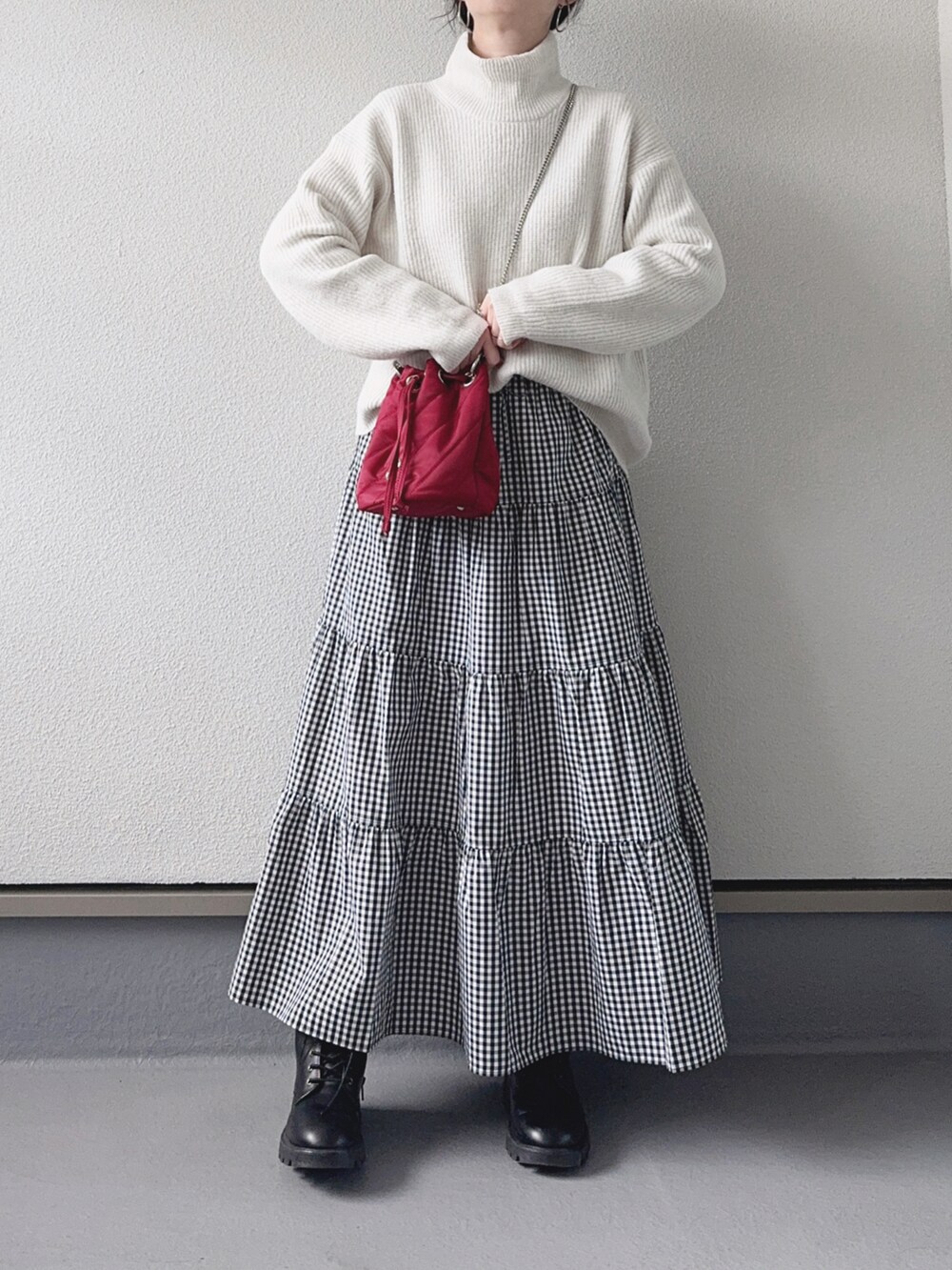 ホワイト系のニット/セーター、ブラック系のスカート、レッド系のハンドバッグを着用したレディースの冬コーディネートの2枚目の写真