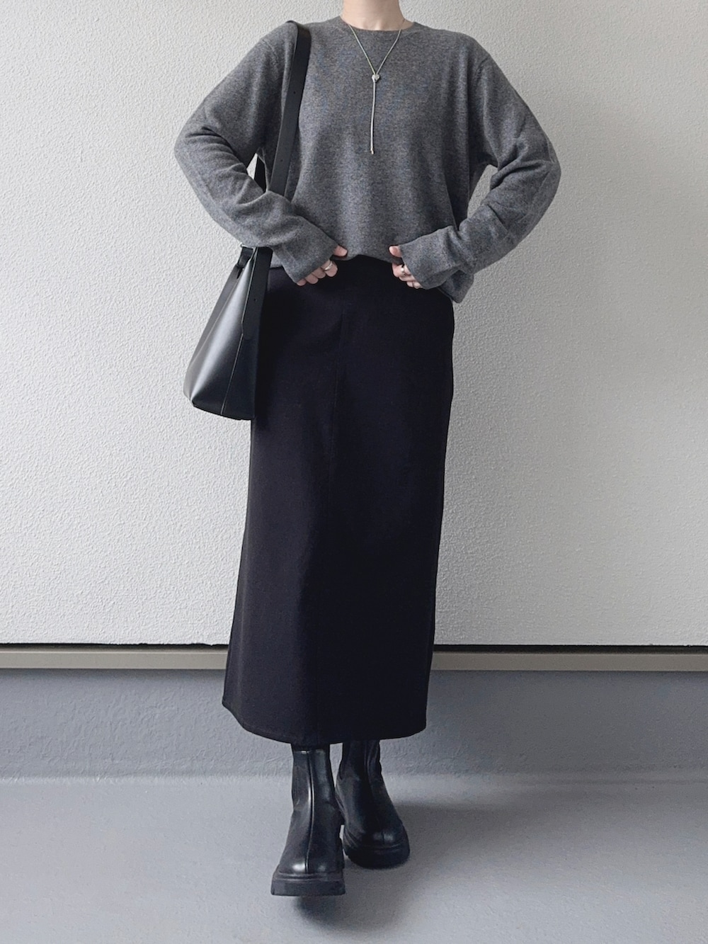 グレー系のニット/セーター、ブラック系のスカート、ブラック系のショルダーバッグを着用したレディースの秋コーディネートの2枚目の写真