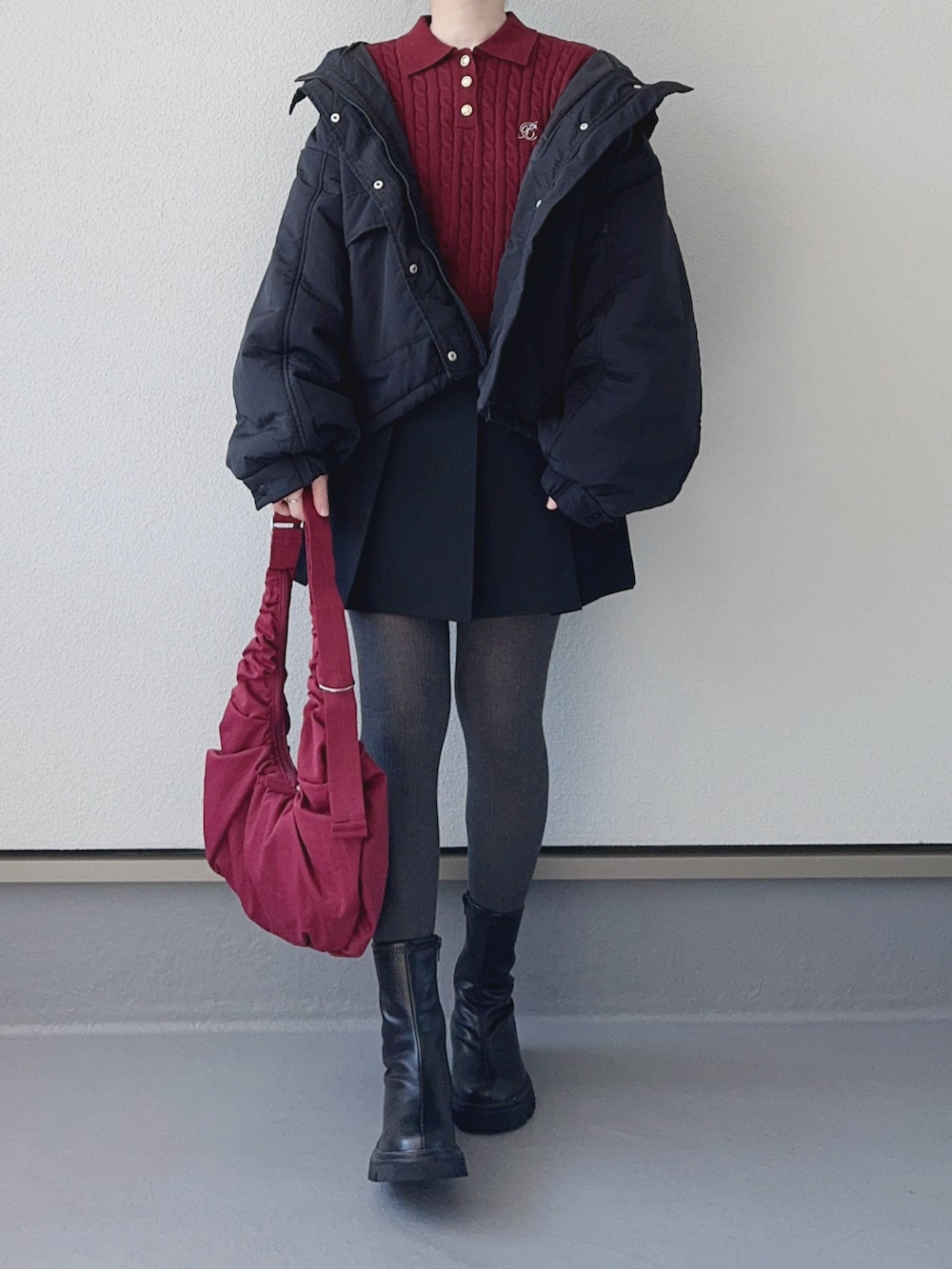 レッド系のニット/セーター、ブラック系のブルゾン、ブラック系のブーツを着用したレディースの秋コーディネートの2枚目の写真