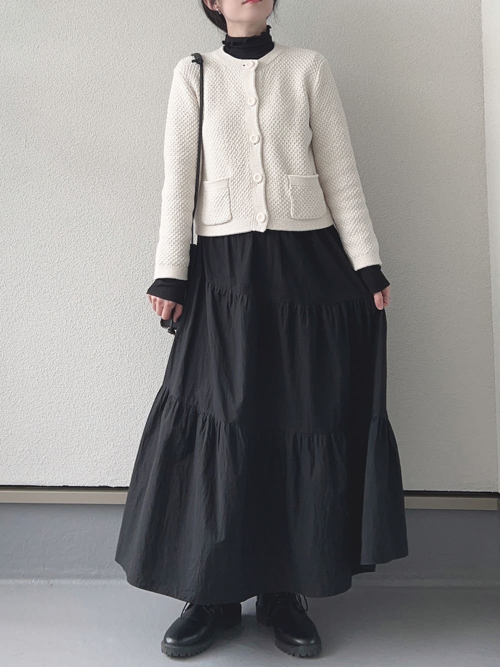 ホワイト系のカーディガン/ボレロ、ブラック系のTシャツ/カットソー、ブラック系のスカートを着用したレディースの冬コーディネートの2枚目の写真