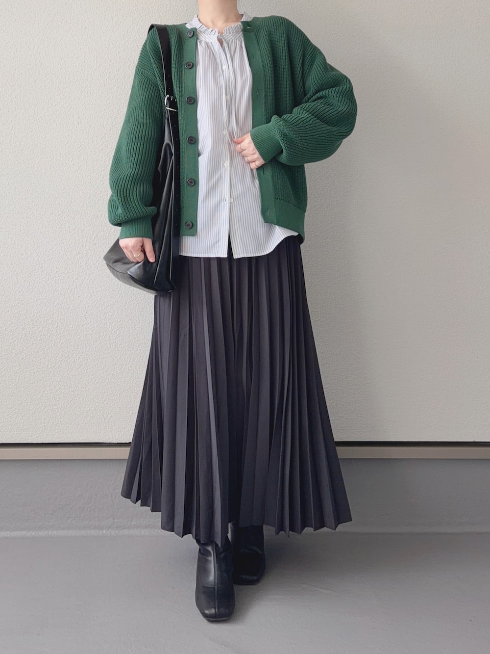 グレー系のスカート、グレー系のシャツ/ブラウス、グリーン系のカーディガン/ボレロを着用したレディースの冬コーディネートの2枚目の写真