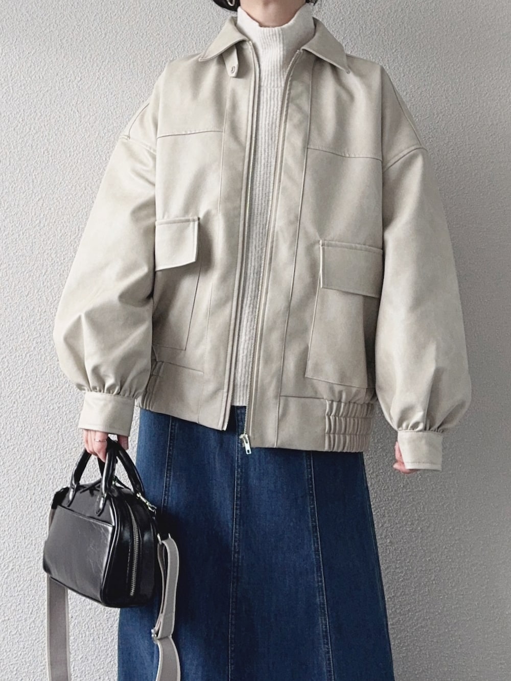 ホワイト系のブルゾン、ホワイト系のニット/セーター、ブルー系のデニムスカートを着用したレディースの冬コーディネートの3枚目の写真