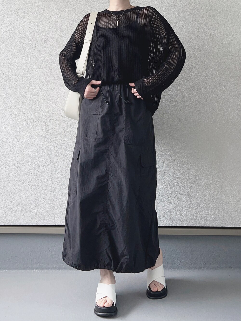 ブラック系のニット/セーター、ブラック系のスカート、ホワイト系のバッグを着用したレディースの春コーディネートの3枚目の写真