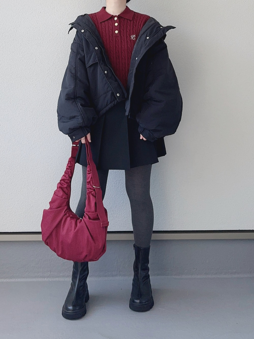 レッド系のニット/セーター、ブラック系のブルゾン、ブラック系のブーツを着用したレディースの秋コーディネートの3枚目の写真