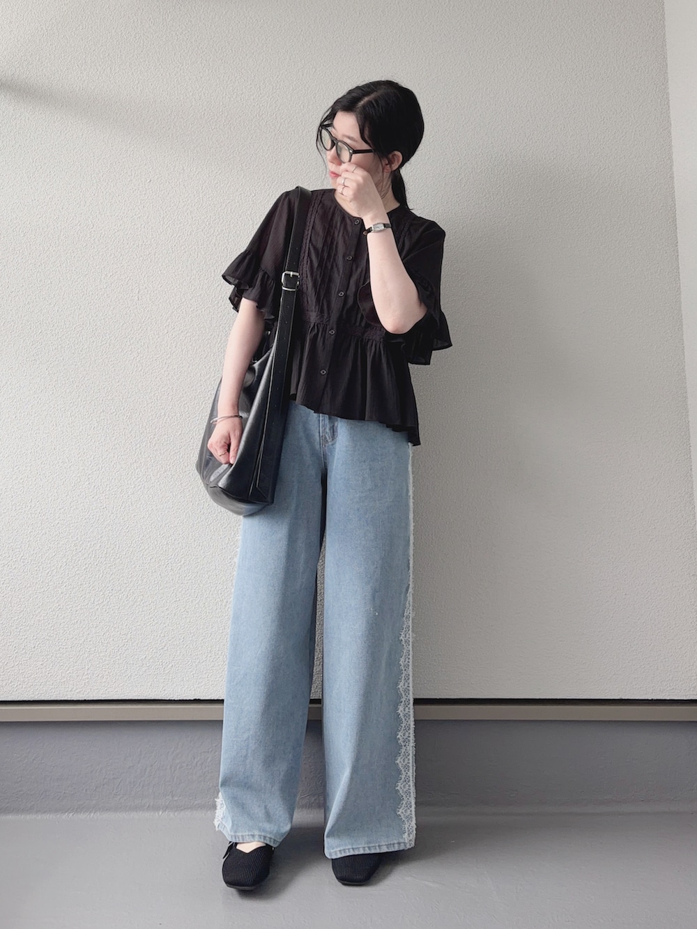 ブルー系のデニムパンツ、ブラック系のシャツ/ブラウス、ブラック系のショルダーバッグを着用したレディースの夏コーディネートの5枚目の写真