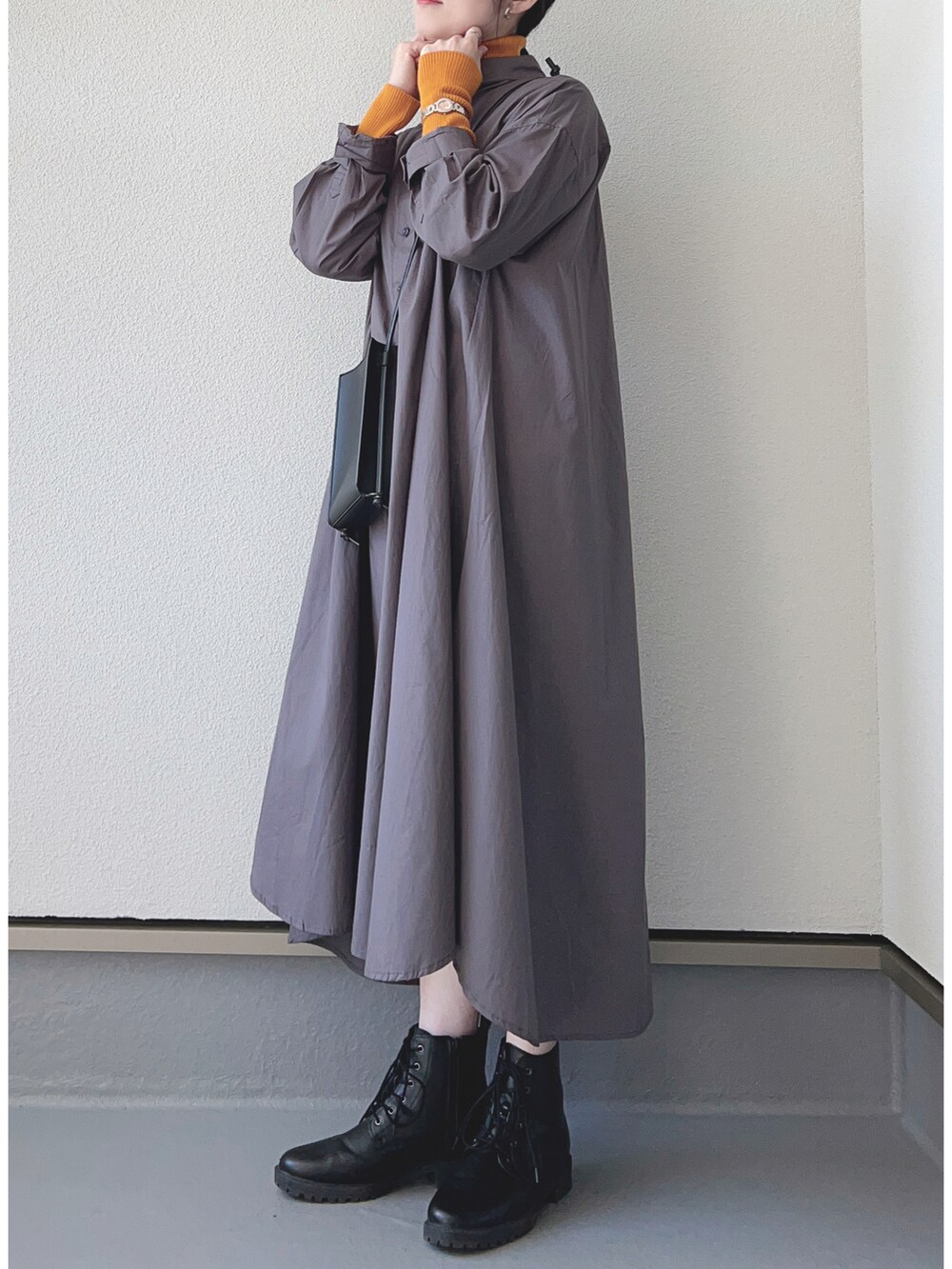 ブラック系のシャツワンピース、オレンジ系のニット/セーター、ブラック系のブーツを着用したレディースの秋コーディネートの2枚目の写真