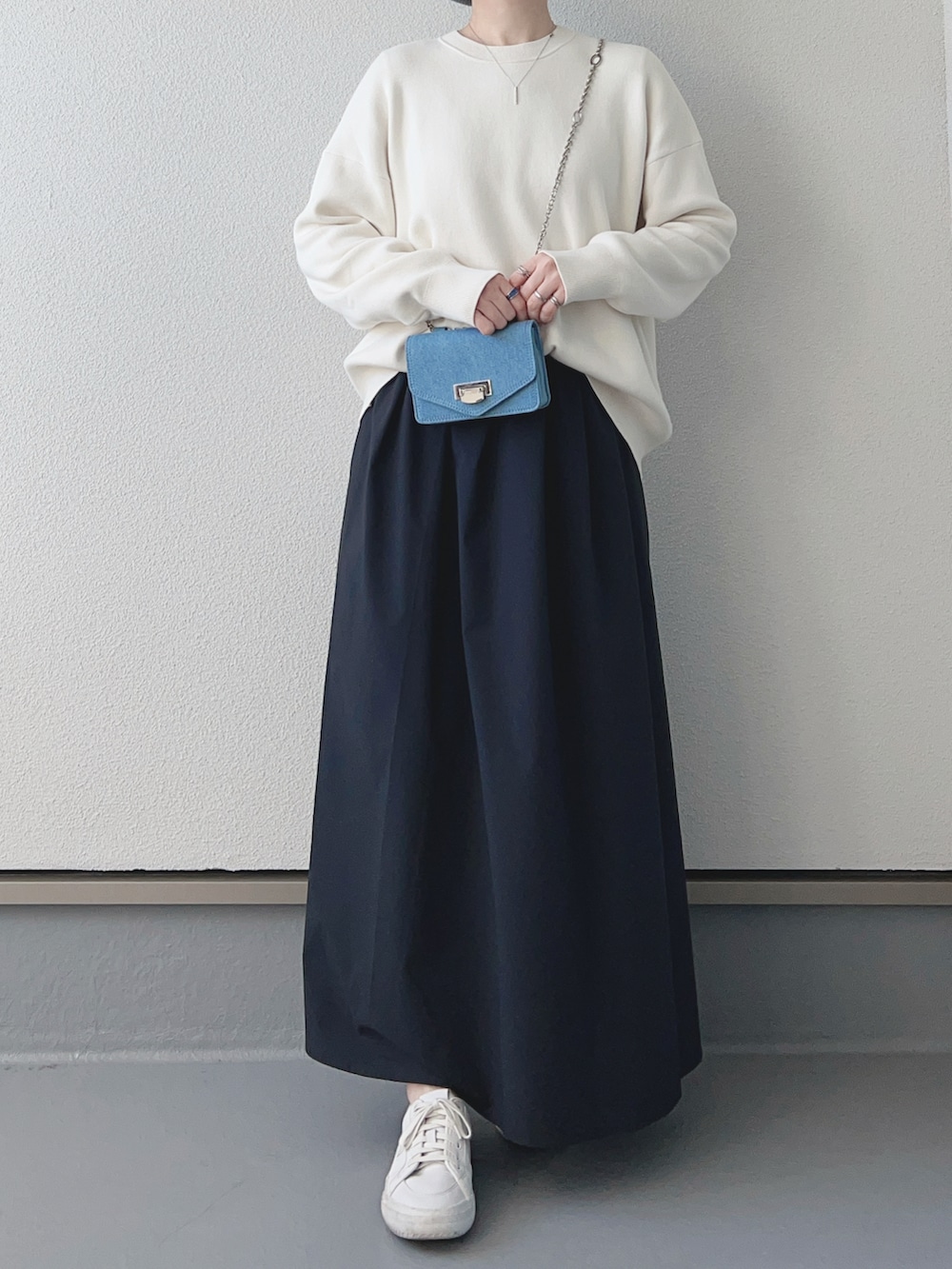 ホワイト系のニット/セーター、ブラック系のスカート、ブルー系のショルダーバッグを着用したレディースの冬コーディネートの3枚目の写真