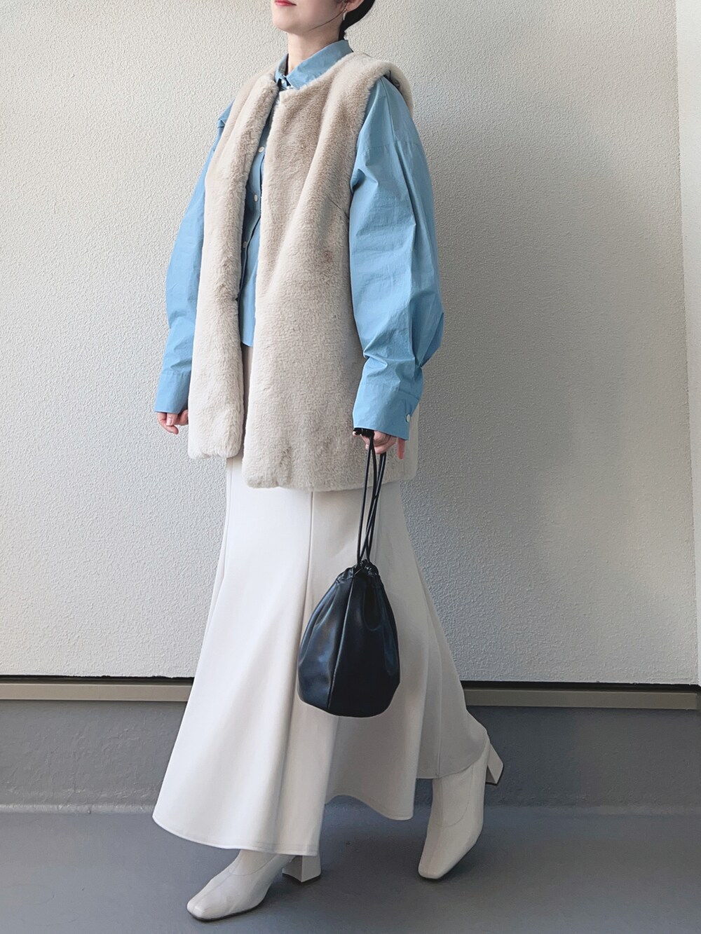 グレー系のベスト、ブルー系のシャツ/ブラウス、ホワイト系のスカートを着用したレディースの冬コーディネートの3枚目の写真