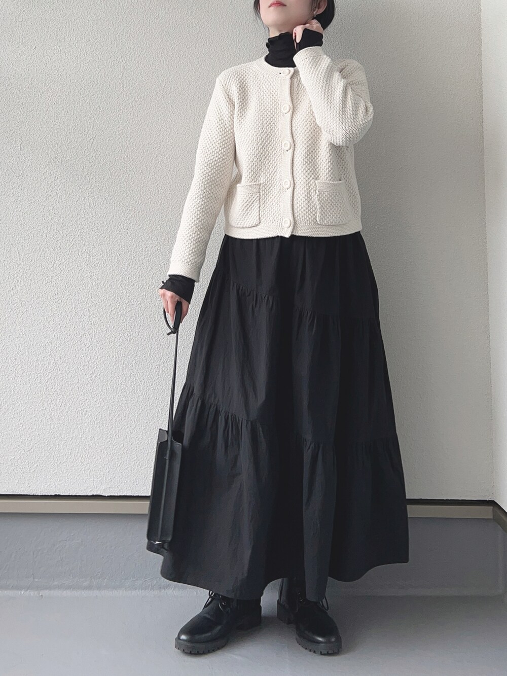 ホワイト系のカーディガン/ボレロ、ブラック系のTシャツ/カットソー、ブラック系のスカートを着用したレディースの冬コーディネートの3枚目の写真