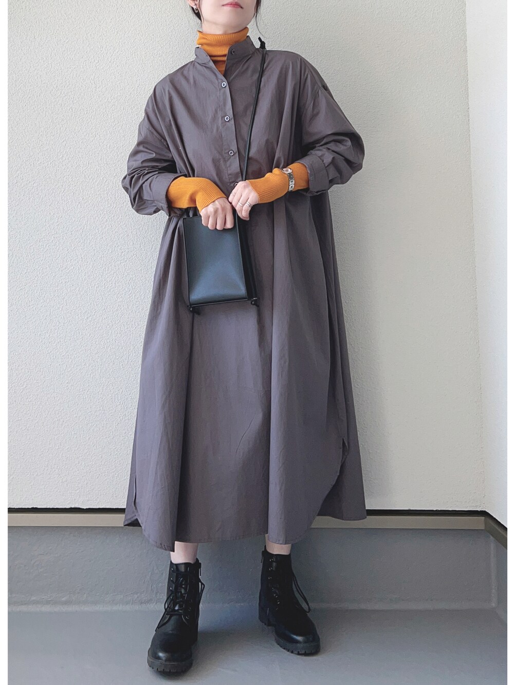 ブラック系のシャツワンピース、オレンジ系のニット/セーター、ブラック系のブーツを着用したレディースの秋コーディネートの3枚目の写真