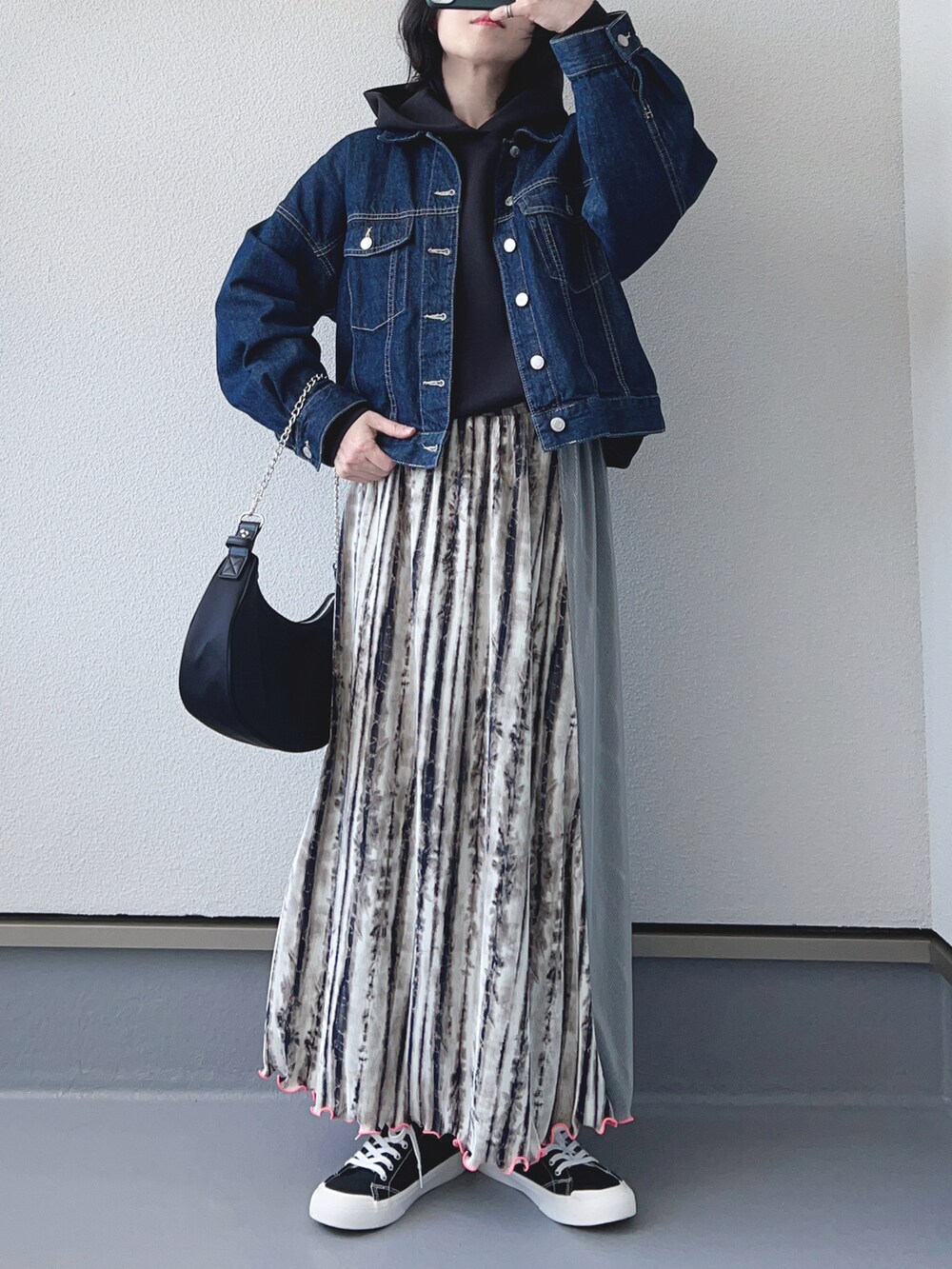 ベージュ系のスカート、ブラック系のスウェット、ブルー系のデニムジャケットを着用したレディースの春コーディネートの2枚目の写真