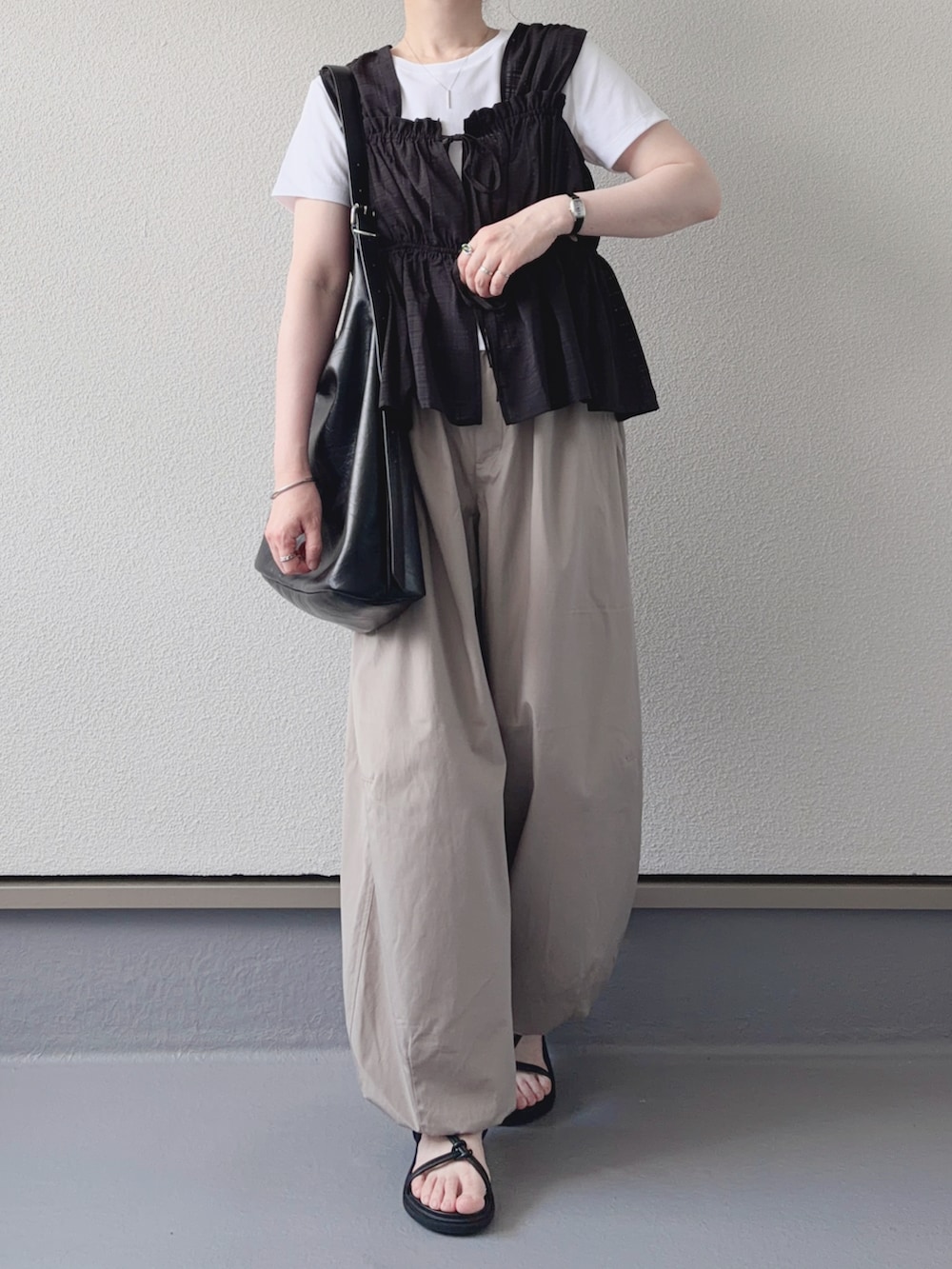 ブラック系のシャツ/ブラウス、ホワイト系のTシャツ/カットソー、ベージュ系のパンツを着用したレディースの夏コーディネートの3枚目の写真