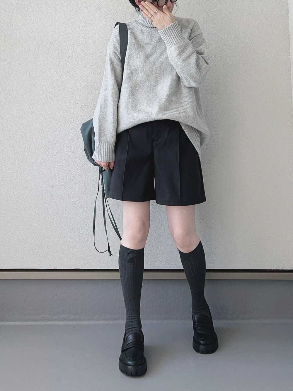 グレー系のニット/セーター、グレー系のパンツ、グリーン系のバッグを着用したレディースの秋コーディネートの2枚目の写真