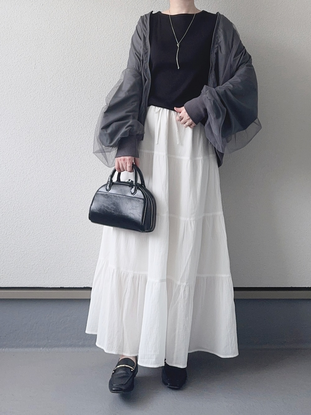 グレー系のブルゾン、ブラック系のTシャツ/カットソー、ホワイト系のスカートを着用したレディースの春コーディネートの3枚目の写真