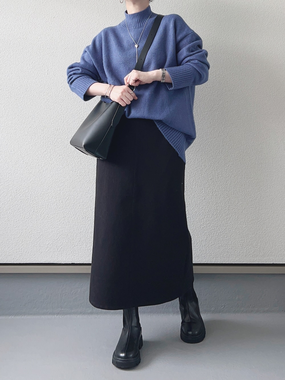 ブルー系のニット/セーター、ブラック系のスカート、ブラック系のショルダーバッグを着用したレディースの秋コーディネートの2枚目の写真