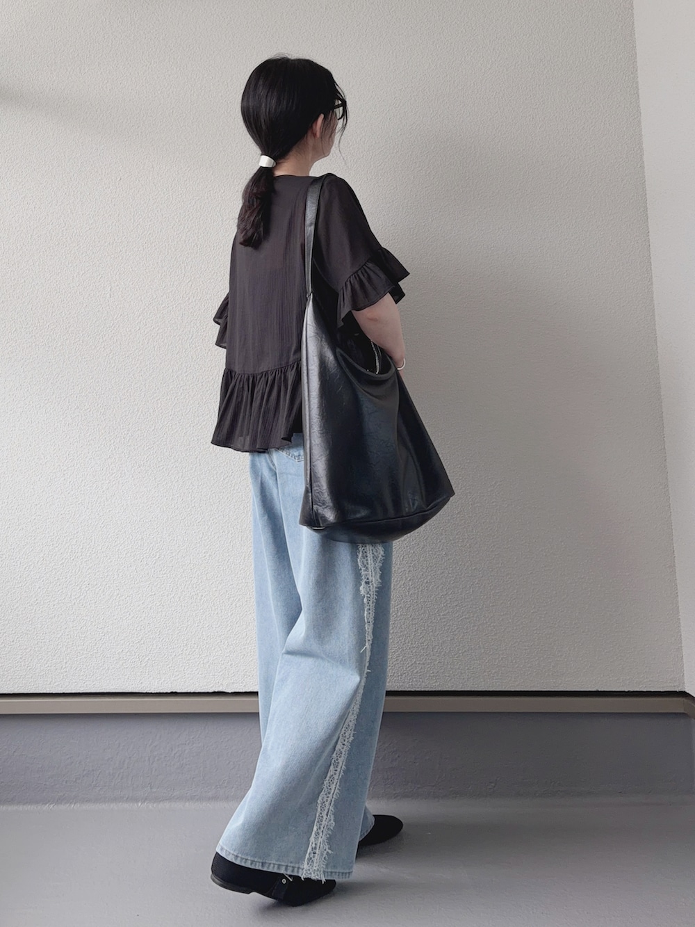 ブルー系のデニムパンツ、ブラック系のシャツ/ブラウス、ブラック系のショルダーバッグを着用したレディースの夏コーディネートの3枚目の写真