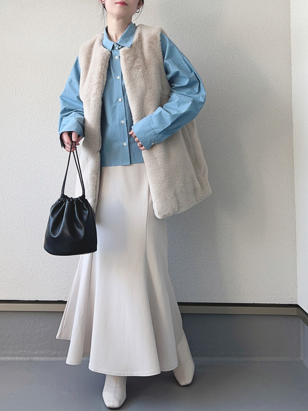 グレー系のベスト、ブルー系のシャツ/ブラウス、ホワイト系のスカートを着用したレディースの冬コーディネートの2枚目の写真