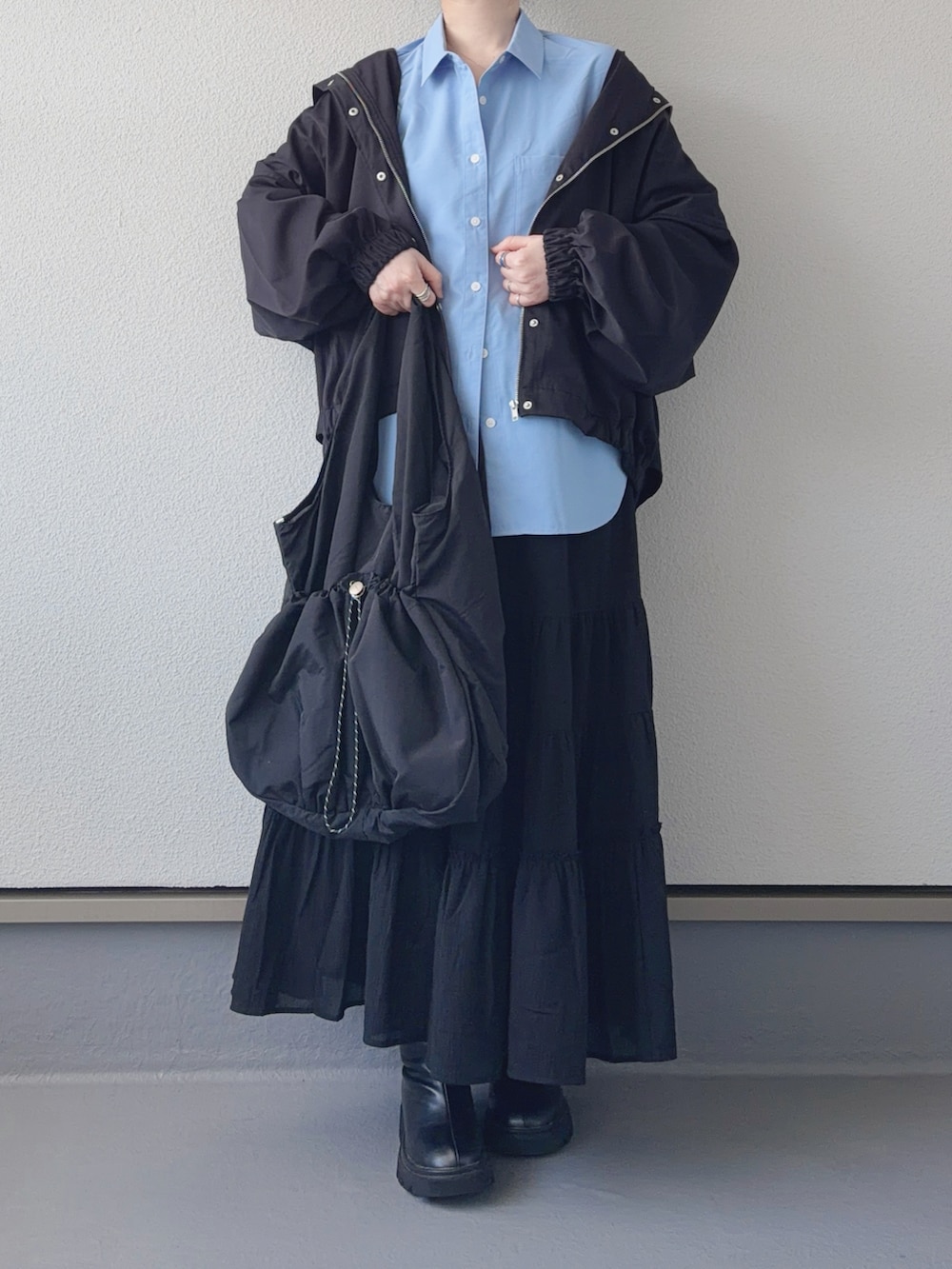 ブラック系のマウンテンパーカー、ブラック系のブーツ、ブラック系のトートバッグを着用したレディースの春コーディネートの4枚目の写真