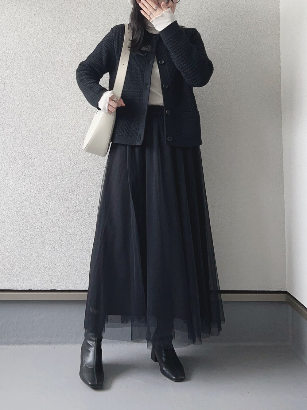 ブラック系のスカート、ブラック系のカーディガン/ボレロ、ホワイト系のバッグを着用したレディースの冬コーディネートの3枚目の写真
