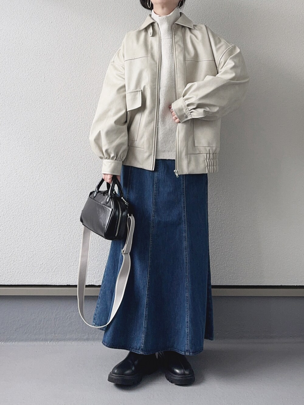 ホワイト系のブルゾン、ホワイト系のニット/セーター、ブルー系のデニムスカートを着用したレディースの冬コーディネートの2枚目の写真