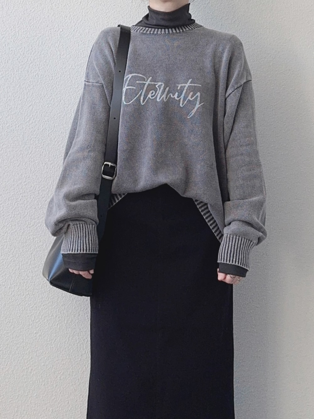 ブラック系のニット/セーター、グレー系のTシャツ/カットソー、ブラック系のスカートを着用したレディースの秋コーディネートの3枚目の写真