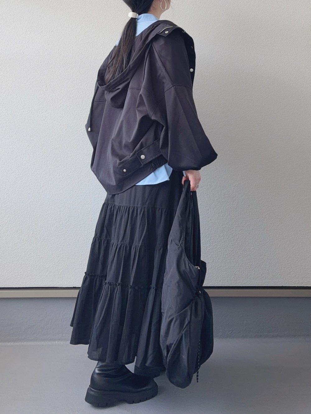 ブラック系のマウンテンパーカー、ブラック系のブーツ、ブラック系のトートバッグを着用したレディースの春コーディネートの3枚目の写真