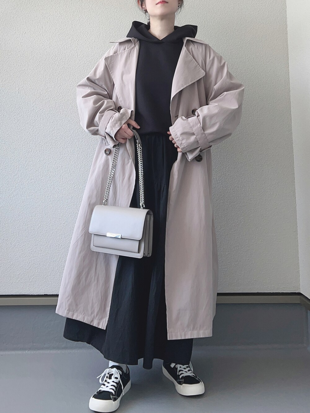 ベージュ系のトレンチコート、ブラック系のスウェット、ブラック系のスカートを着用したレディースの春コーディネートの2枚目の写真