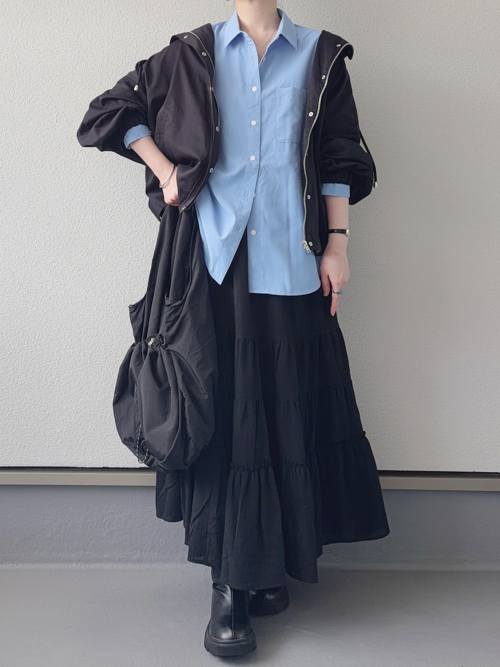 ブラック系のマウンテンパーカー、ブラック系のブーツ、ブラック系のトートバッグを着用したレディースの春コーディネートの2枚目の写真