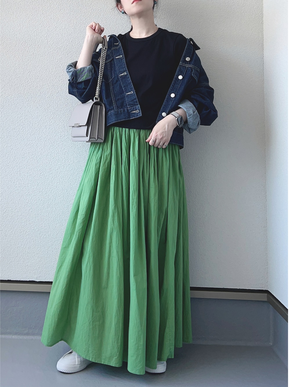 ブルー系のデニムジャケット、ブラック系のTシャツ/カットソー、グリーン系のスカートを着用したレディースの秋コーディネートの2枚目の写真