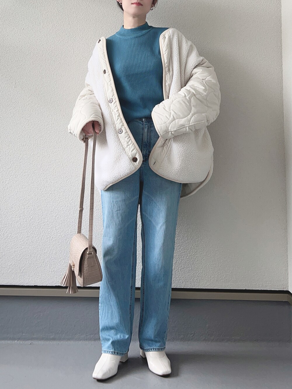 ホワイト系のノーカラージャケット、ブルー系のニット/セーター、ブルー系のデニムパンツを着用したレディースの冬コーディネートの2枚目の写真