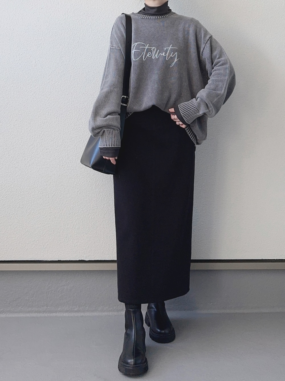 ブラック系のニット/セーター、グレー系のTシャツ/カットソー、ブラック系のスカートを着用したレディースの秋コーディネートの2枚目の写真