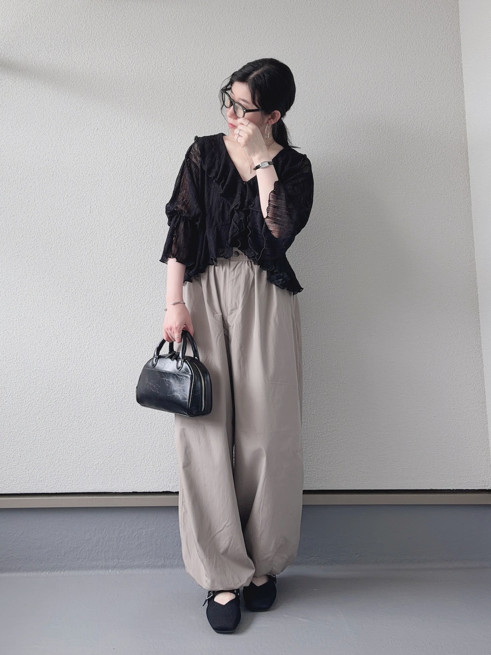 ブラック系のカーディガン/ボレロ、ベージュ系のパンツ、ブラック系のショルダーバッグを着用したレディースの夏コーディネートの4枚目の写真