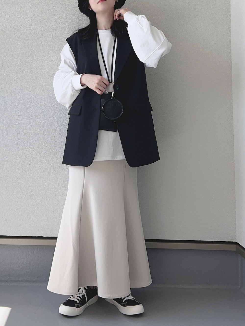 ブラック系のベスト、ホワイト系のTシャツ/カットソー、ブラック系のショルダーバッグを着用したレディースの春コーディネートの2枚目の写真