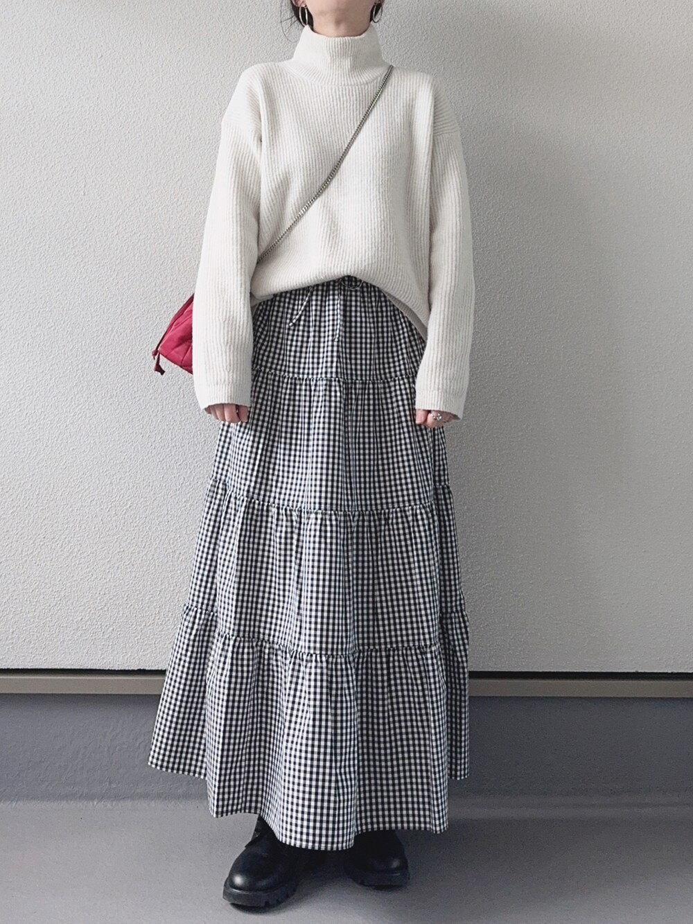 ホワイト系のニット/セーター、ブラック系のスカート、レッド系のハンドバッグを着用したレディースの冬コーディネートの3枚目の写真