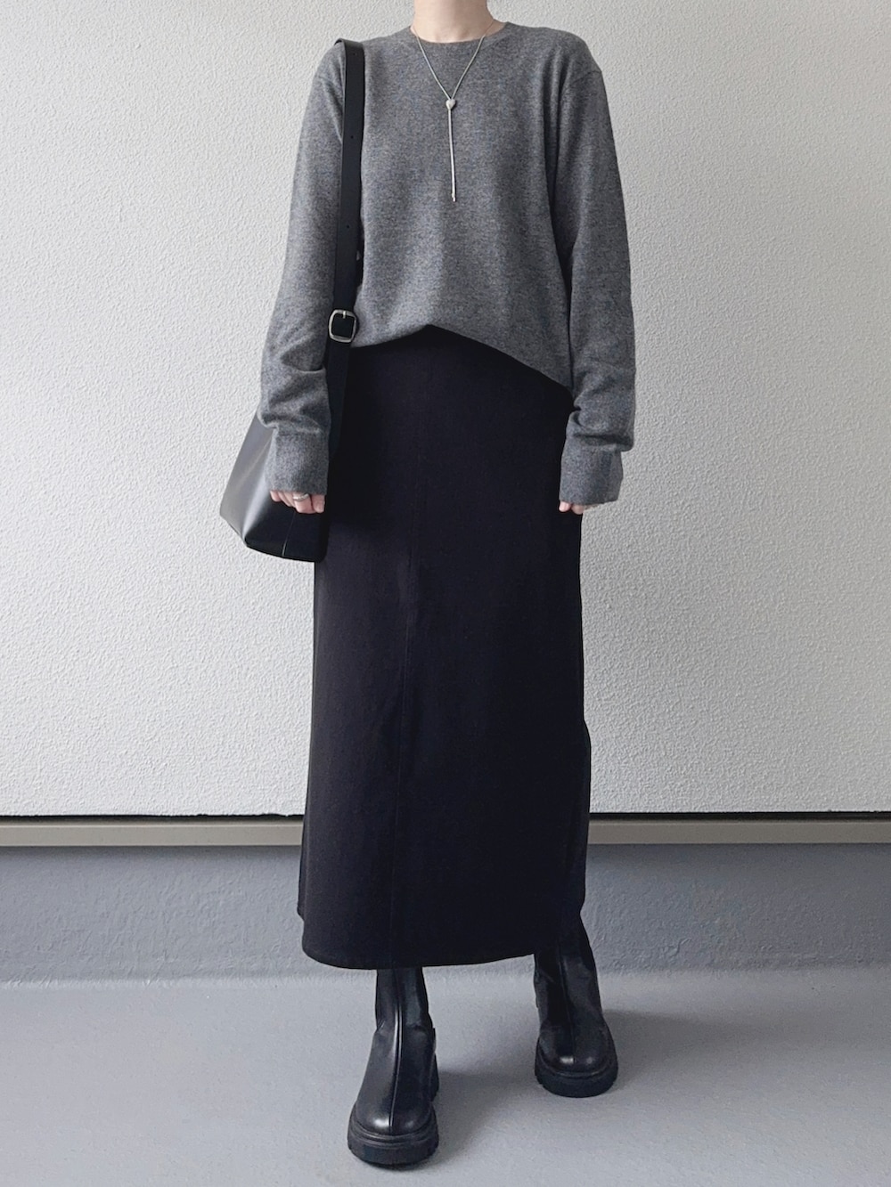 グレー系のニット/セーター、ブラック系のスカート、ブラック系のショルダーバッグを着用したレディースの秋コーディネートの3枚目の写真