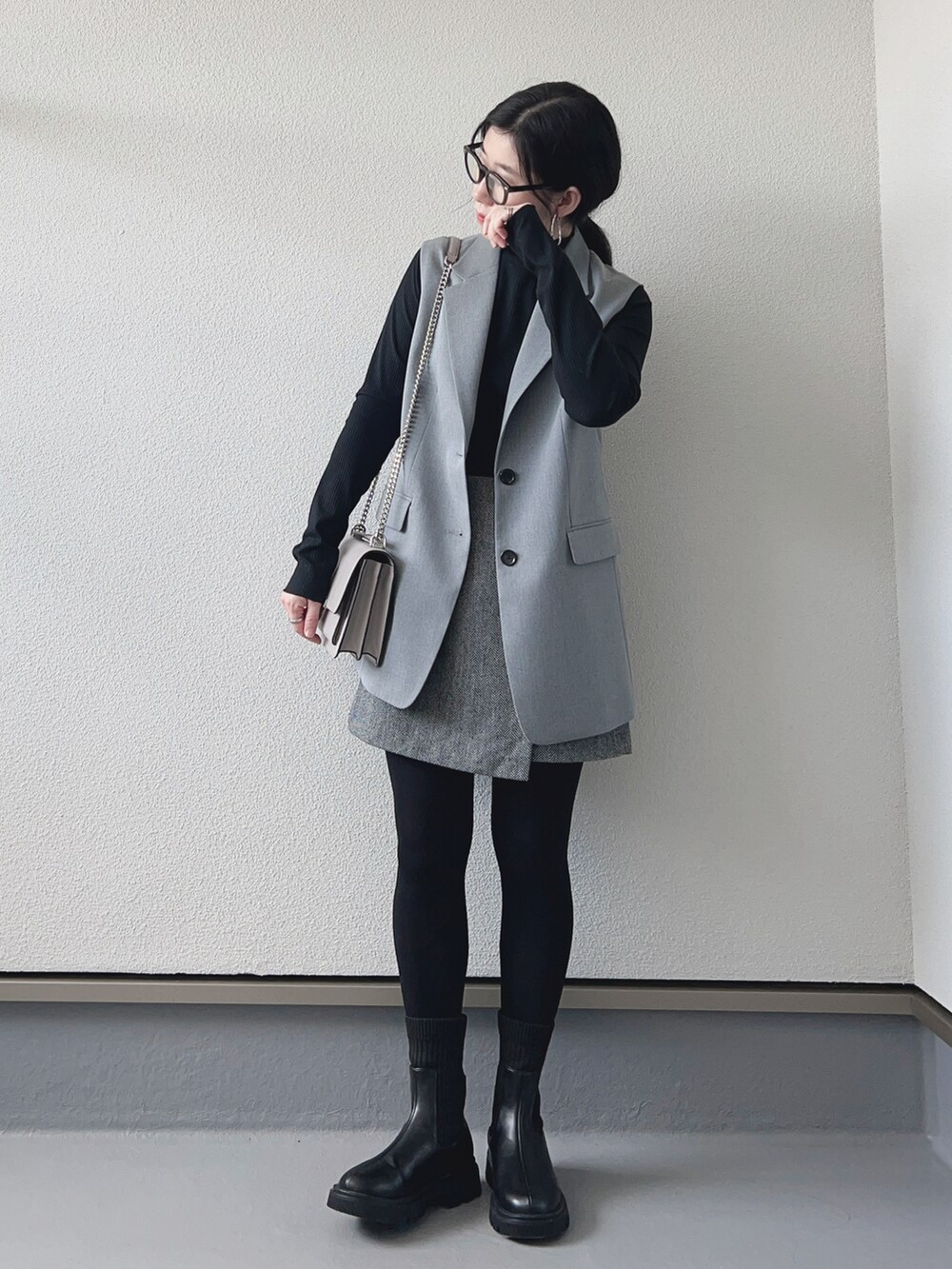 ブラック系のTシャツ/カットソー、グレー系のベスト、グレー系のスカートを着用したレディースの秋コーディネートの2枚目の写真