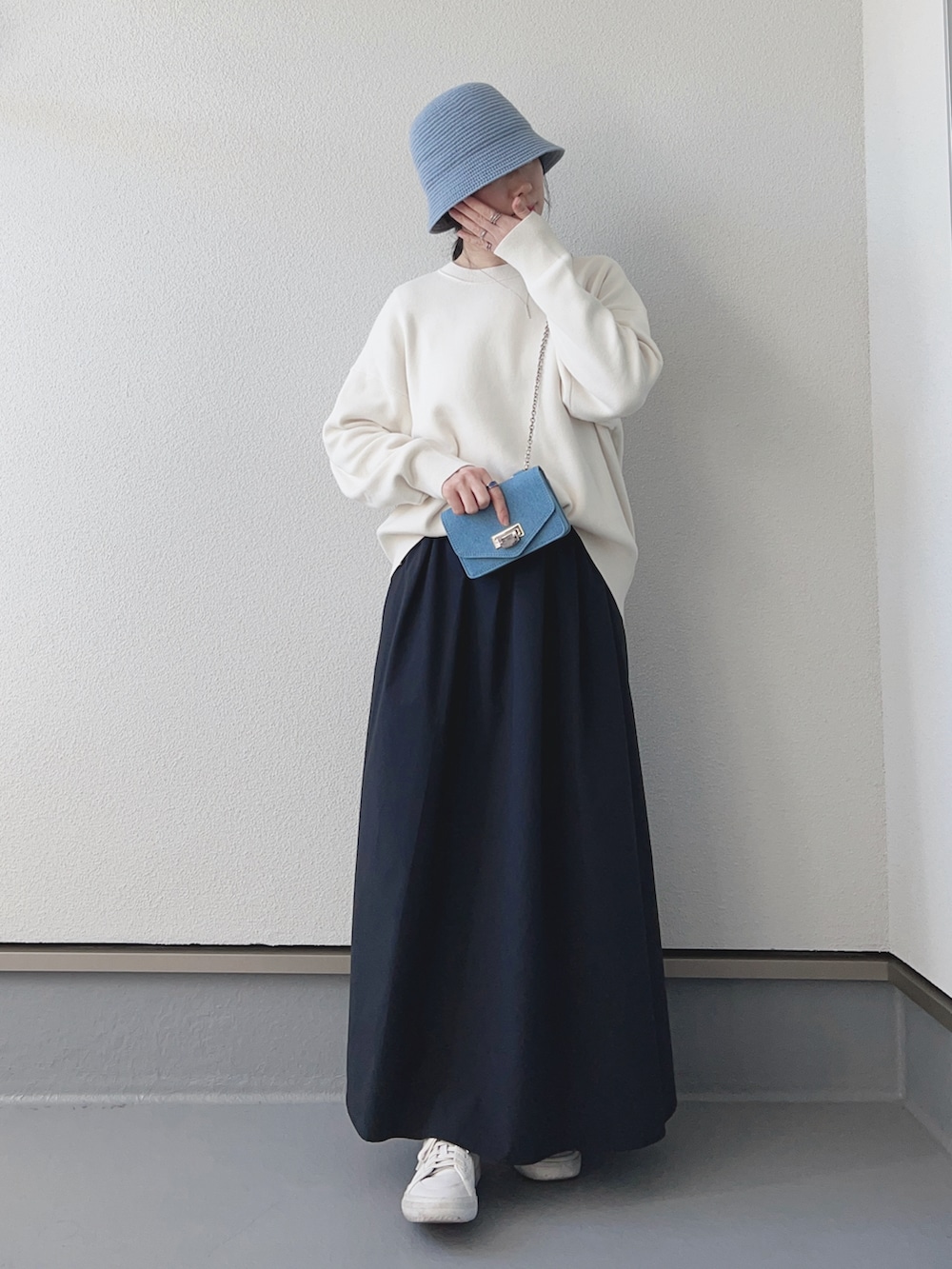 ホワイト系のニット/セーター、ブラック系のスカート、ブルー系のショルダーバッグを着用したレディースの冬コーディネートの2枚目の写真