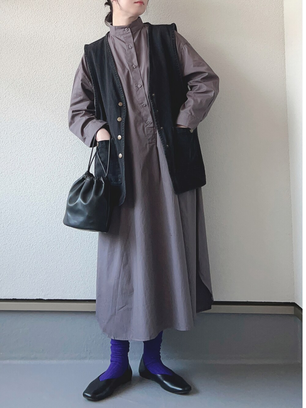 ブラック系のシャツワンピース、ブラック系のベスト、ホワイト系のショルダーバッグを着用したレディースの秋コーディネートの2枚目の写真