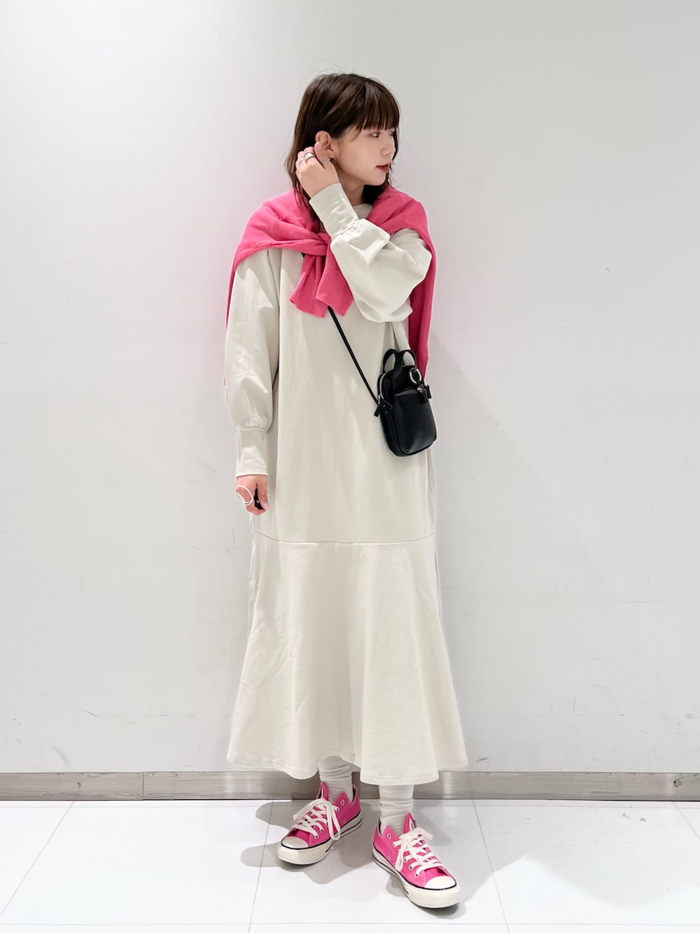 ホワイト系のワンピース、ピンク系のカーディガン/ボレロ、ブラック系のショルダーバッグを着用したレディースの春コーディネートの2枚目の写真