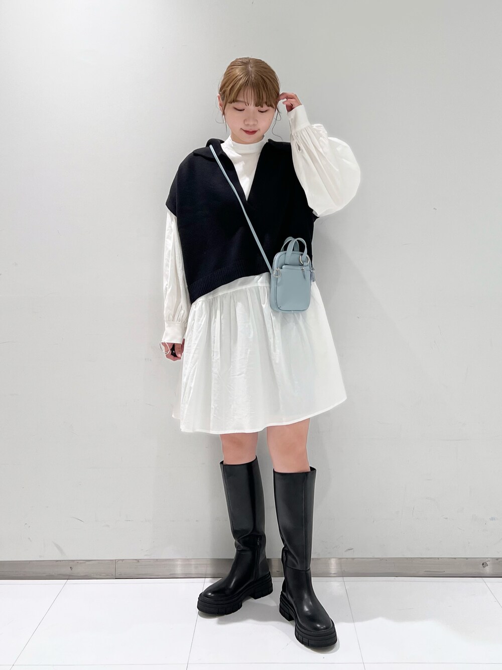 ホワイト系のシャツ/ブラウス、ブラック系のベスト、ブラック系のブーツを着用したレディースの春コーディネートの2枚目の写真