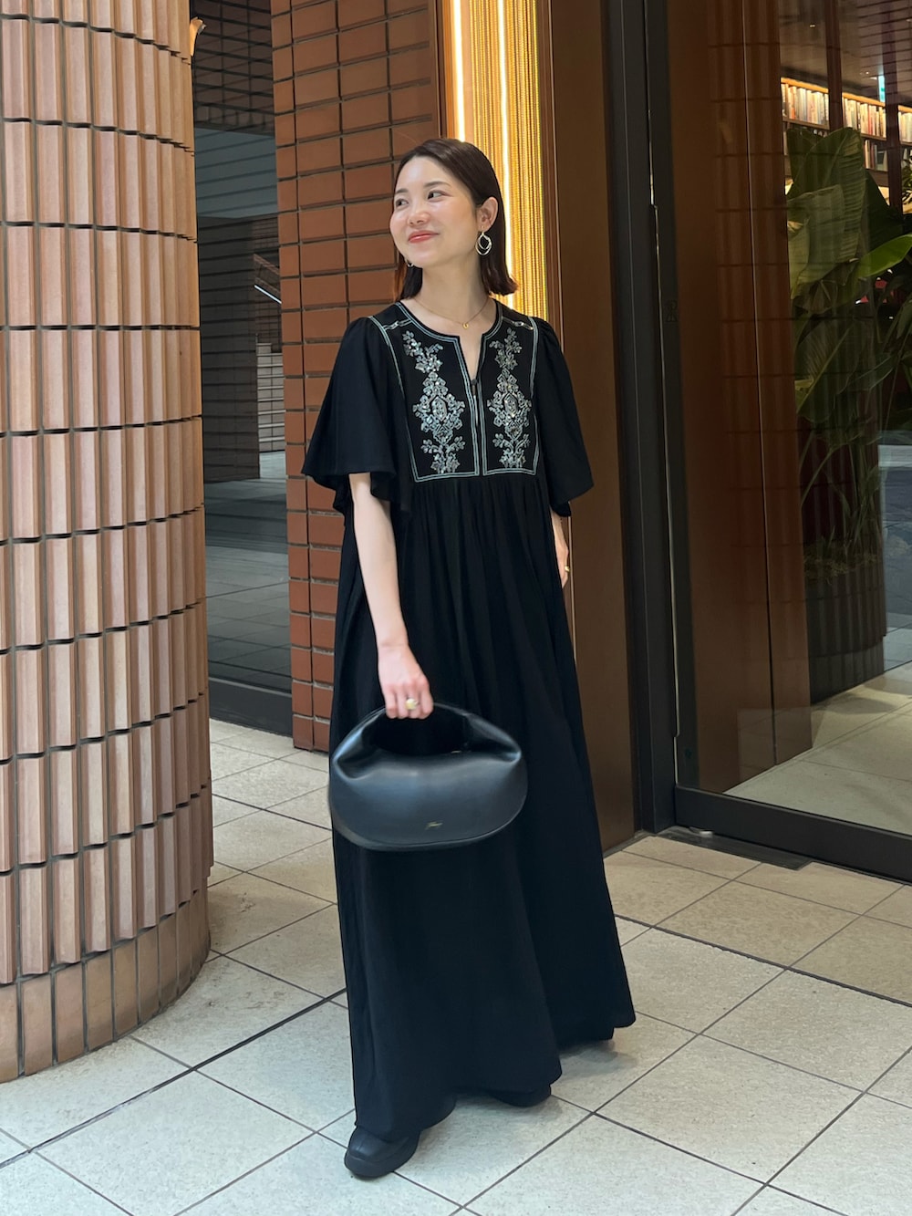 ブラック系のワンピースを着用したレディースの春コーディネートの2枚目の写真
